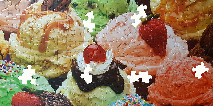 ice cream scoops with jigsaw pieces cut out and a cherry and strawberry on top
