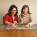 two women doing a puzzle on a wood table